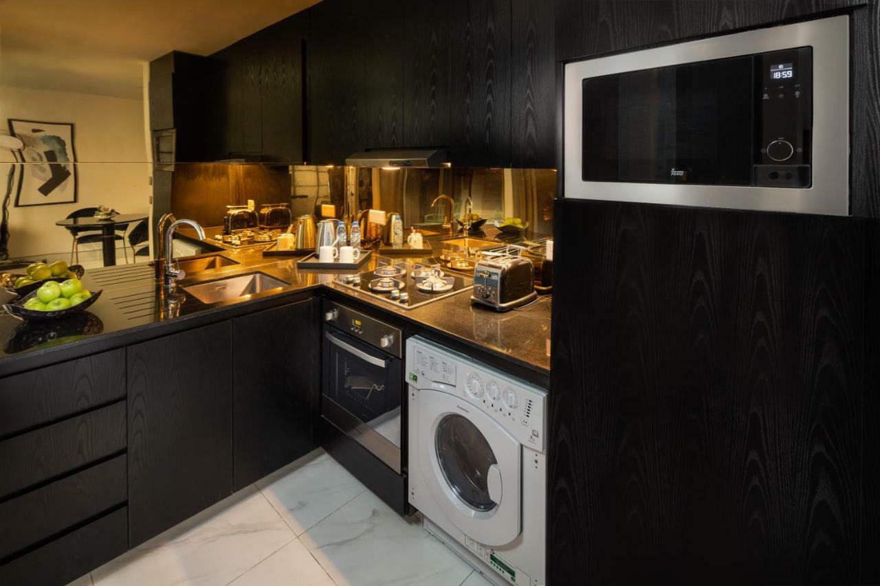 Millennium Atria Business Bay Aparthotel Dubai Exterior photo The photo shows a modern kitchen with a sleek design. The cabinets and surfaces are predominantly black, creating a contemporary look. There is a stainless steel microwave mounted above the countertop, and on the counter, various kitchen appliances l